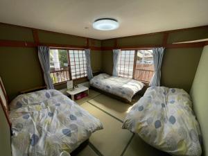 a room with two beds and two windows at EZO HOUSE in Kawayu