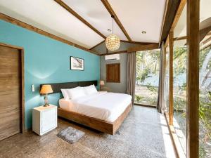 a bedroom with a bed and a large window at Villa Harimau-Original Joglo style 3B with pool in Gili Trawangan