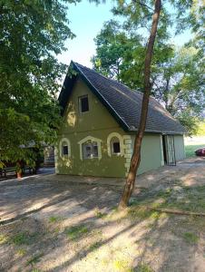 a green house with a tree in front of it at Sumski raj Gornje podunavlje in Sombor