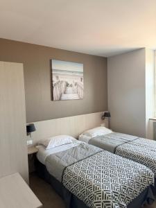 a hotel room with two beds and a picture on the wall at Au bon saint Nicolas in Hillion
