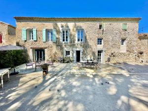 a large stone building with tables and benches in front of it at Mas du Rocan in Aubignan