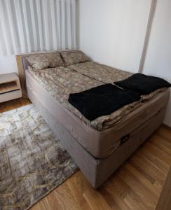 an unmade bed in a room with a rug at Apartmani Savić expres Laktasi in Laktaši