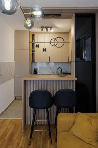 a kitchen with a bar with two chairs and a couch at Apartmani Savić expres Laktasi in Laktaši