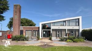 a large brick building with a tall tower at Blom studio's in Hillegom