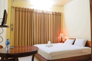 a bedroom with a bed and a table with a table at Dokban Hotel in Luang Prabang