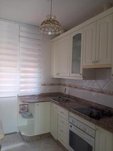 a kitchen with white cabinets and a sink and a chandelier at Casa de Concha in Burela de Cabo