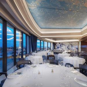 a restaurant with white tables and chairs and windows at Villa Romy, a World apart in Roquebrune-Cap-Martin
