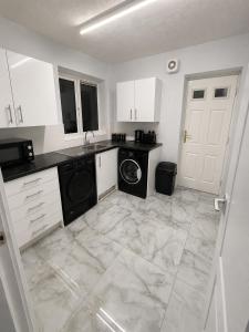 a kitchen with white cabinets and a washer and dryer at Newly Refurbished 3-Bed Sleeps 5 in Lostock