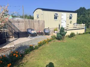 a backyard with two chairs and a fence at Whitethorn Shepherds Hut in Bellaghy