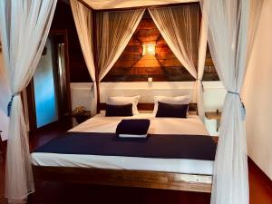 a bedroom with a canopy bed with curtains at Mahanoro Hotel & Restaurant in Sainte Marie