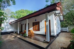 a small white house with a wooden deck at Mountain Edge By Yala Odyssey in Kataragama