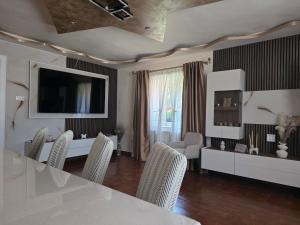 a living room with a table and chairs and a television at Pensiunea Monady in Zărneşti