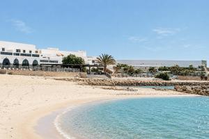 a beach with blue water and buildings in the background at Hotel Buenavista Dakhla in Dakhla