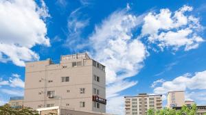 a tall white building with a blue sky and clouds at Busan Go House Pension in Busan