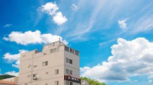 a tall white building with a blue sky and clouds at Busan Go House Pension in Busan