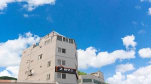 a tall white building with the sky in the background at Busan Go House Pension in Busan