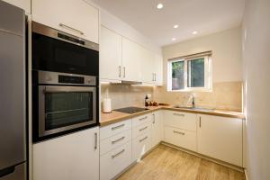 a kitchen with white cabinets and a sink and a microwave at Villa Idola Dassia Corfu in Dassia