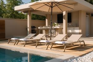 a group of lounge chairs and an umbrella next to a pool at Villa Idola Dassia Corfu in Dassia +40 photos