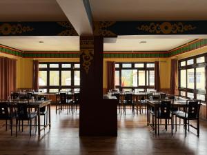 a dining room with tables and chairs and windows at Lecoxy Resort in Lachung