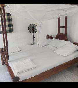 a bedroom with two beds and a clock on the wall at Kwetu nungwi in Kinyasini