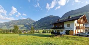 a house in a field with mountains in the background at Gästehaus WOLFGARTEN in Sankt Jakob in Defereggen +4 photos