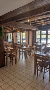 a restaurant with wooden tables and chairs and windows at L'auberge des Érables in La Pesse