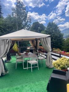 a patio with a table and chairs under a canopy at Apartament Casa cu Flori de Munte in Buşteni +7 photos