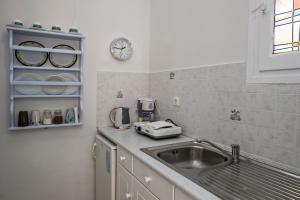 una cocina con fregadero y un reloj en la pared en Prasino Oniro, en Tinos