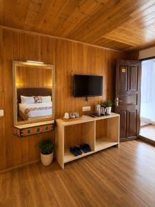 a bedroom with a bed with a mirror and a television at Lecoxy Resort in Lachung