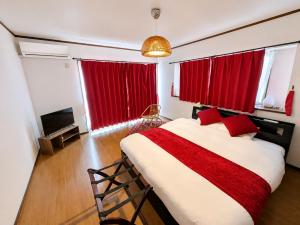 a bedroom with a large bed with red curtains at Atagohama seaside House in Fukuoka