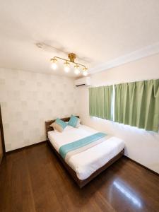 a bedroom with a large bed with a green curtain at Atagohama seaside House in Fukuoka