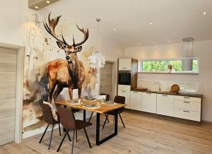 a kitchen with a table with a deer mural on the wall at Gartenbungalow Rhönwild in Hilders