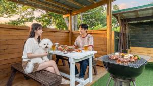 a man and a woman sitting at a table with a dog at boryeong hiddenvillage dokchae poolvilla in Boryeong