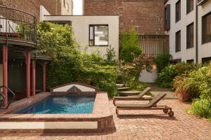 a backyard with a swimming pool and two lounge chairs at Latroupe Hotel Jardin Secret in Brussels