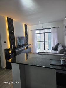a kitchen with a counter top and a living room at Kitusiru Falls Retreat, in Kanyongo