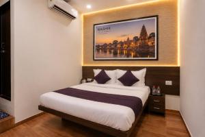 a bedroom with a bed with a picture on the wall at Hotel Dwarka Executive in Nashik +33 photos