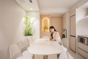 a woman sitting at a white table in a kitchen at 더하다 in Busan