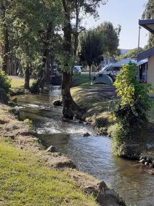 a stream of water next to a road with a tree at Tente lodge in Brassac