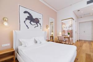 a white bedroom with a white bed and a table at Apartamenty Bracka 6 in Krakow