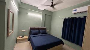 a bedroom with a blue bed and a ceiling fan at FabHotel Metro Stay in Kolkata