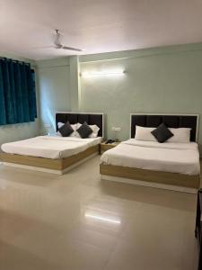 two beds in a room with at FabHotel Metro Stay in Kolkata