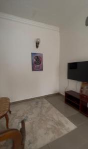 a living room with a television and a white wall at Bk House in Pointe-Noire