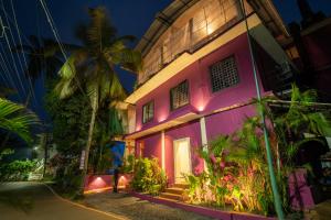 a pink building with a door and a palm tree at Seraya Stays in Mandrem
