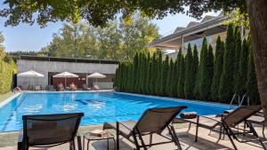 a swimming pool with chairs and a house at Oca Puerta del Camino Hotel in Santiago de Compostela
