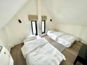 two beds in a room with white sheets at Milky house in Ban Bang Phai