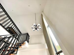 a staircase with a chandelier in a house at Milky house in Ban Bang Phai