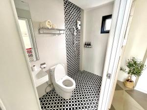 a bathroom with a toilet and a black and white tile floor at Milky house in Ban Bang Phai