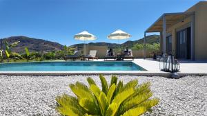 a swimming pool with people sitting in chairs next to a house at Villa Emanouill Nopigia in Kissamos