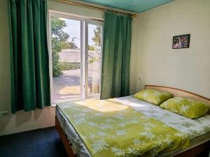 a bedroom with a bed and a window with green curtains at Asian Guest House in Bishkek