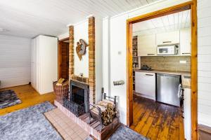 a living room with a fireplace and a kitchen at Cottage kingfisher 